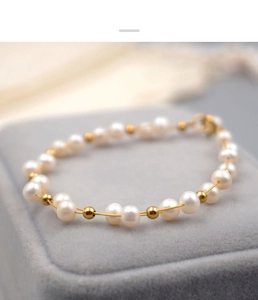 Macro detail of elegant freshwater pearl bracelet with gold beads on grey velvet jewelry box