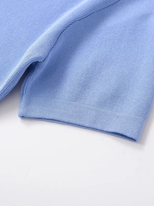 Close-up of light blue knit top showing fine texture and hem stitching on white background