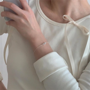 Close-up of a 925 sterling silver bow bracelet on a wrist with a soft aesthetic vibe