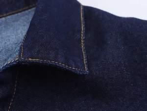 Detailaufnahme von Kragen und weißen Nähten auf einem dunkelblauen Jeanshemd