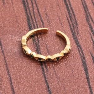 Detail of gold plated open ring featuring embedded emerald green marquise gemstones