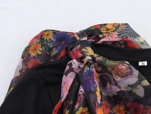 Detail of round neckline with organza bow tie and floral print on women's black top