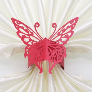 Detail of red laser-cut butterfly paper napkin ring on a white satin cloth