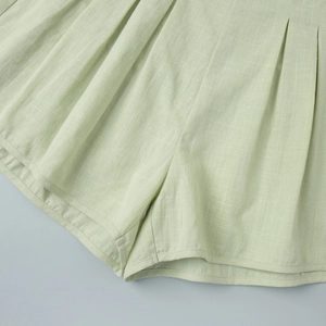 Macro detail of pleated cotton-linen high-waisted shorts in light pistachio green