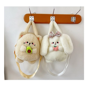 Plush cat and rabbit crossbody bags with avocado and peach details on a wooden hanger