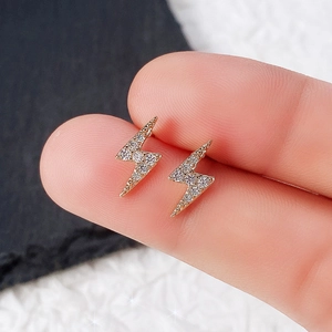 Close-up of mini lightning bolt stud earrings with cubic zirconia held by fingers