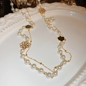 Double-layered gold necklace featuring white pearls and camellia flower pendant details