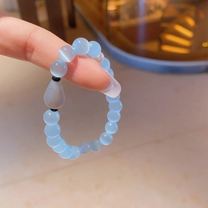 Detailed view of light blue cat eye beaded bracelet with a white teardrop charm