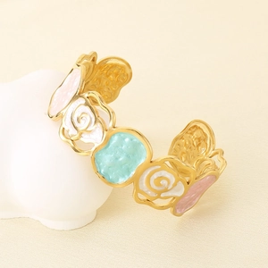 Close-up of golden enamel bangle featuring embossed pink and white rose floral patterns
