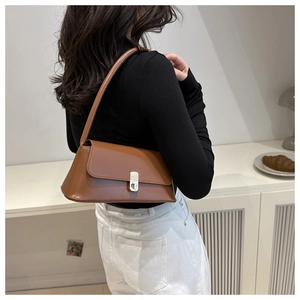 Brown PU leather shoulder bag with gold metal buckle shown on model in natural light