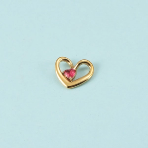 Détail d'un pendentif cœur doré évidé orné d'une pierre de naissance rose