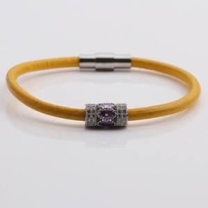 Detail of yellow braided leather bracelet with silver bead and purple stone inlay