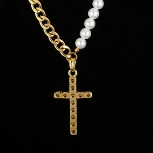 Détail du collier chaîne cubaine dorée avec perles blanches et pendentif croix en cristal