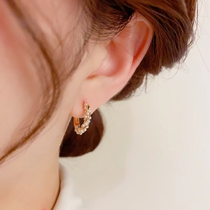 Elegant C-shaped baroque seed pearl hoop earrings with gold twisted rope design on model