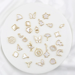 Macro shot of 18k gold butterfly and moon pendants with mother of pearl and zircon details