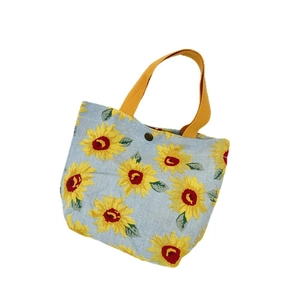Light blue sunflower print tote bag with yellow handles and snap closure on white background