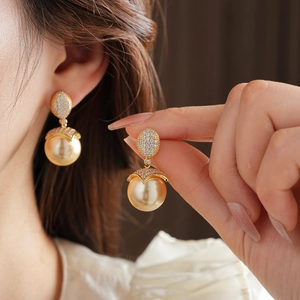 Dettaglio degli orecchini di perle placcati oro 18 carats con diamanti indossati