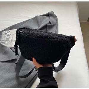 Close-up of black plush waist bag with adjustable strap and small orange side label detail