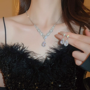 Macro shot of silver zircon teardrop necklace and earrings set on an elegant model