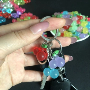 Handheld cherry keychain featuring colorful resin charms in red, purple and blue