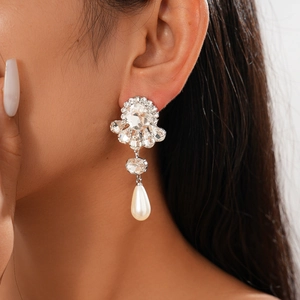 Close-up of Baroque earrings with crystals and drop pearls on a silver base