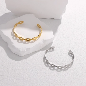 Dettaglio di bracciali a catena in oro e argento esposti su una roccia bianca