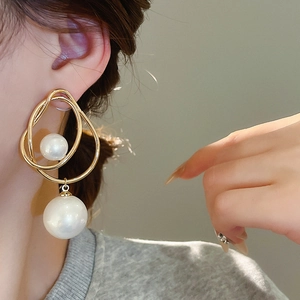 Gros plan de boucles d'oreilles perles dorées croisées sur l'oreille avec finition brillante