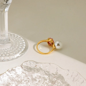 Detail of 18K gold ring featuring a pink oval gemstone and white round pearl