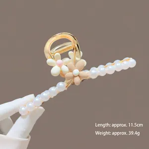 Detail view of 11.5cm golden metal hair claw clip with pearls and flower accents