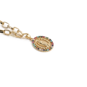 Macro detail of gold Virgin Mary pendant with colorful gemstones and link chain