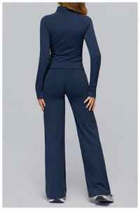 Rear view of dark blue yoga set featuring fitted long sleeve top and flared leggings