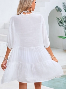 Detail of white tiered ruffle beach dress with tie-back design and linen texture