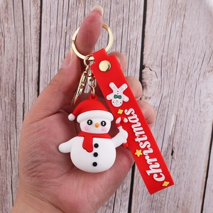 Close-up of a 3D snowman PVC keychain with a red strap and golden metal ring