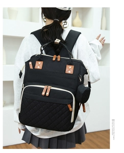Detail of black diaper backpack with quilted front pocket and hanging small coin purse