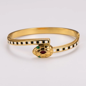 Golden snake-shaped open bangle with black and white enamel and green gemstone eyes