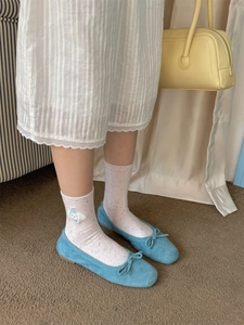 Close-up of white polka dot crew socks with bear embroidery and blue ballet flats
