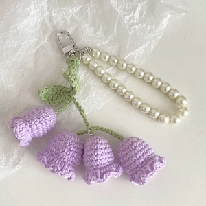 Detail of handmade purple crochet lily of the valley flowers with white pearl chain