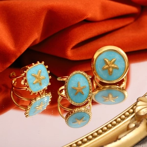 Dreiteiliges Set goldener Seesternringe mit himmelblauer Emaille auf orangefarbener Seide