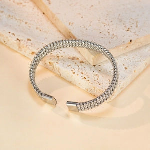 Detail of silver woven mesh stainless steel open cuff bracelet on travertine stone