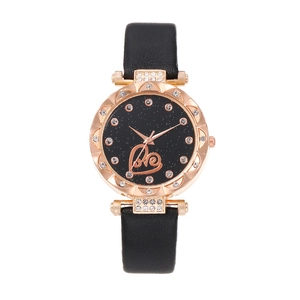 Macro view of starry black watch dial with rose gold Love lettering and crystal accents