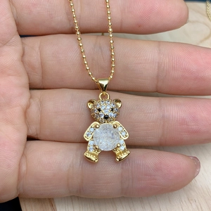 Detail of bear pendant with white zircons and frosted stone on golden bead chain