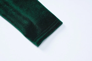 Close-up of stitched cuff detail on dark green velvet long sleeve dress fabric