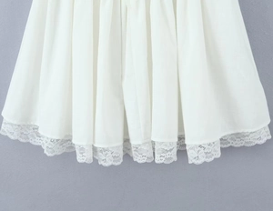 Close-up detail of white dress hem featuring delicate lace trim and soft ruffled fabric