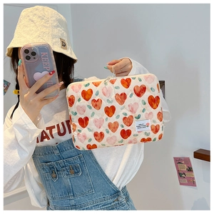 Quilted cotton laptop sleeve with red heart patterns and zipper detail in lifestyle setting