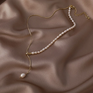Detailed macro view of baroque pearl necklace laid on luxury champagne silk fabric