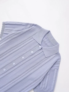 Detailed view of light purple knit polo shirt featuring vertical texture and front buttons