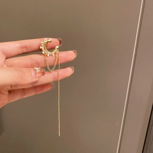 Détail d'un élégant clip d'oreille en perle dorée avec longue chaîne à pompon