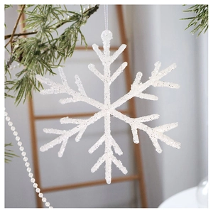 Sparkly white Christmas snowflake ornament hanging on a green pine branch background