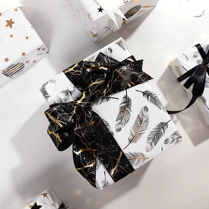 White gift wrapping paper with gold feather prints and black marble ribbons