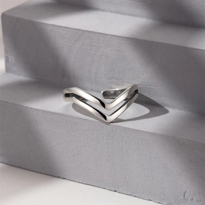Detail of the V-shaped minimalist 925 sterling silver adjustable ring on a grey pedestal